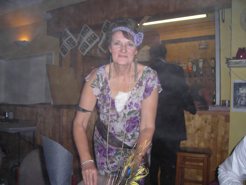 A guest in 1920s dress, with the wood-panelled bar and optics behind her