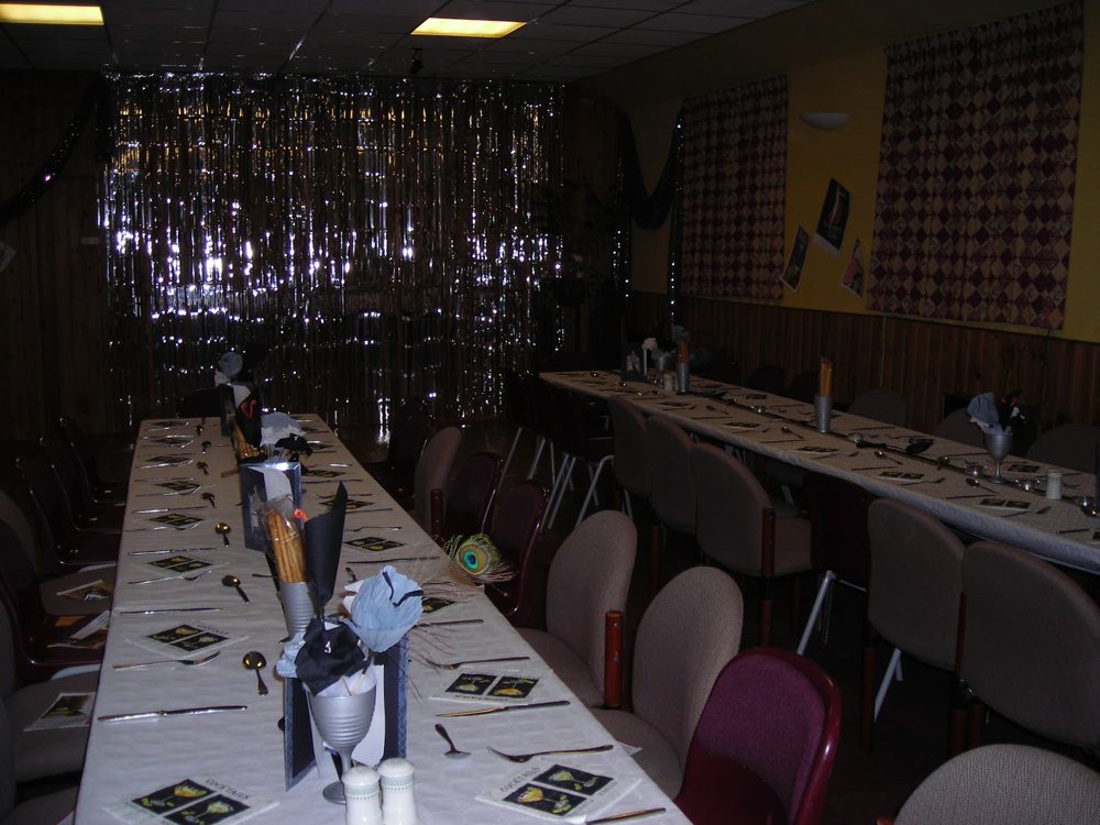 Long tables laid for dinner in the old village hall, with wood panelling and silver streamers