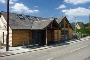 The new Barnes Memorial Hall on the Heyford Road, a timber-clad building with a slate roof and gabled porch