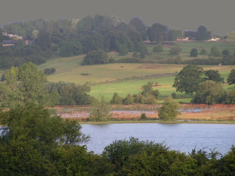 Floodwater lying across the valley meadows, with fields and trees rising on the far side